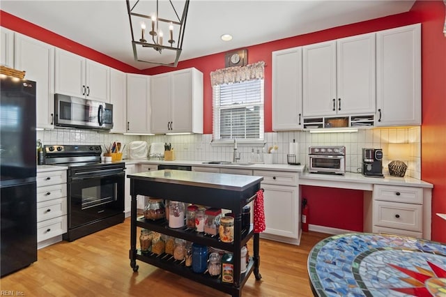 kitchen featuring sink, white cabinetry, tasteful backsplash, pendant lighting, and black appliances