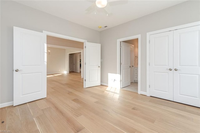 unfurnished bedroom featuring ensuite bath, light hardwood / wood-style floors, a closet, and ceiling fan