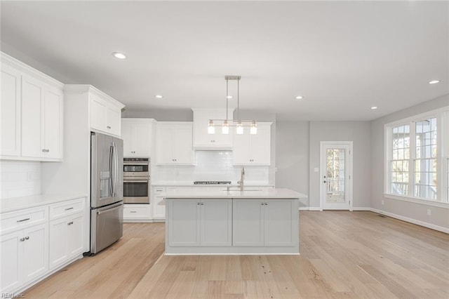 kitchen with hanging light fixtures, appliances with stainless steel finishes, sink, and white cabinets