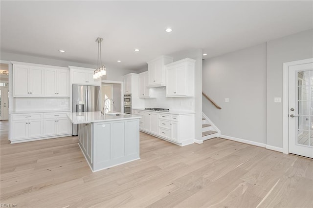 kitchen with sink, white cabinetry, light hardwood / wood-style flooring, appliances with stainless steel finishes, and pendant lighting