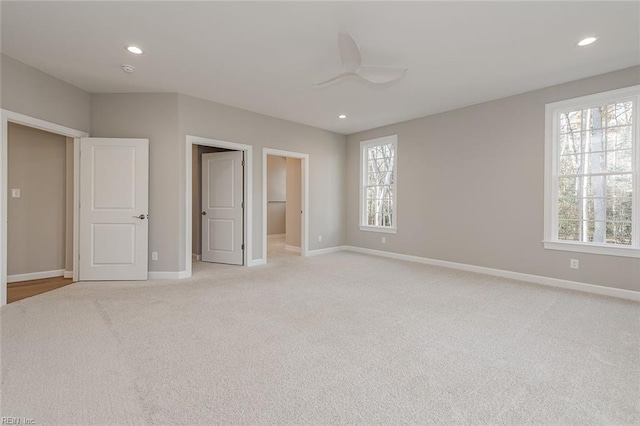 unfurnished bedroom featuring connected bathroom, light colored carpet, and ceiling fan