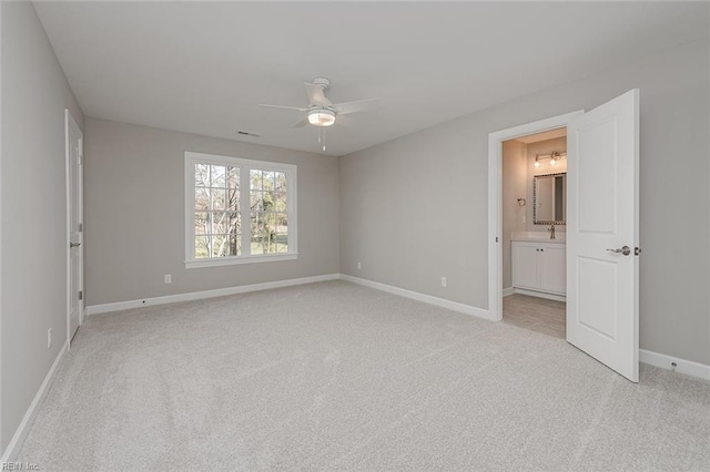 unfurnished bedroom featuring connected bathroom, sink, light carpet, and ceiling fan