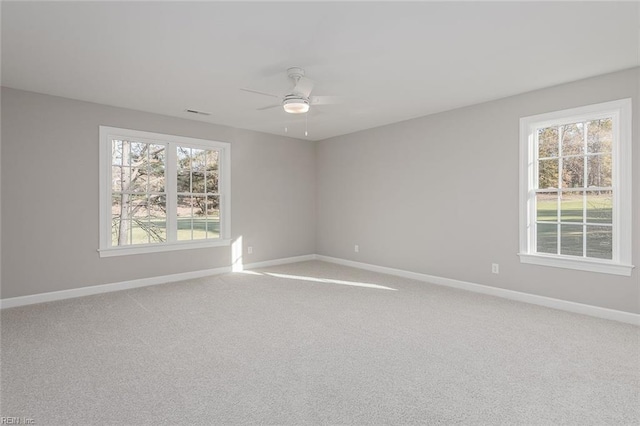 empty room with carpet floors, a wealth of natural light, and ceiling fan