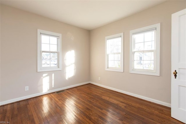 spare room with plenty of natural light and dark hardwood / wood-style floors