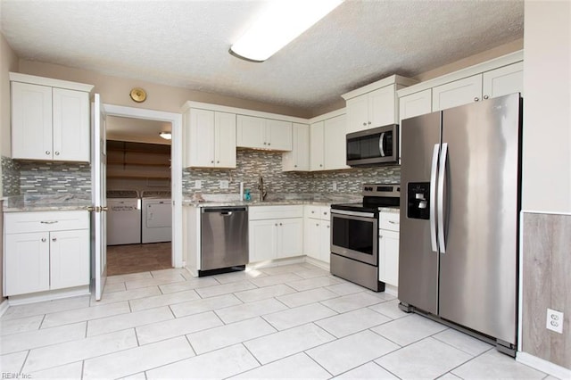 kitchen with white cabinetry, sink, stainless steel appliances, and washer and dryer