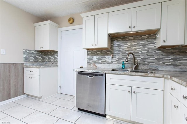 kitchen with light tile patterned flooring, white cabinetry, sink, stainless steel dishwasher, and a textured ceiling