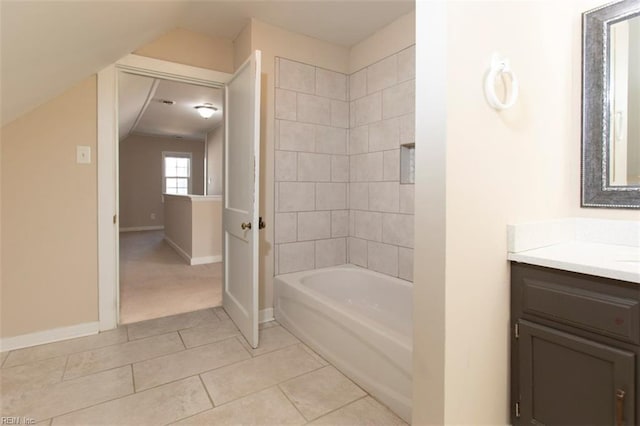 bathroom featuring vaulted ceiling, vanity, tiled shower / bath combo, and tile patterned flooring