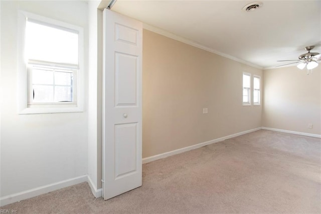 carpeted spare room featuring crown molding and ceiling fan