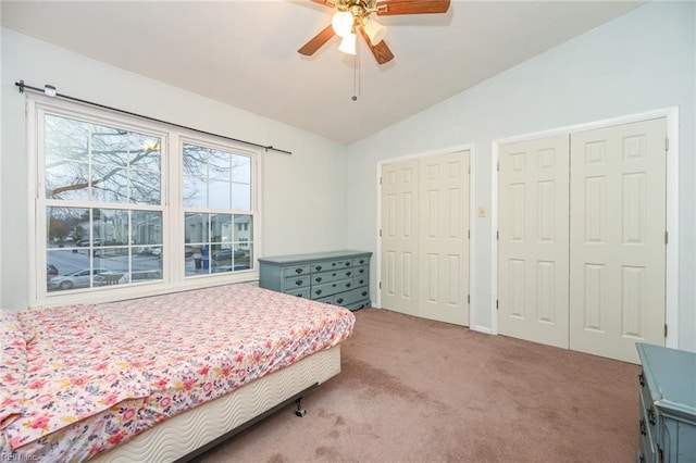 bedroom with ceiling fan, vaulted ceiling, multiple closets, and carpet