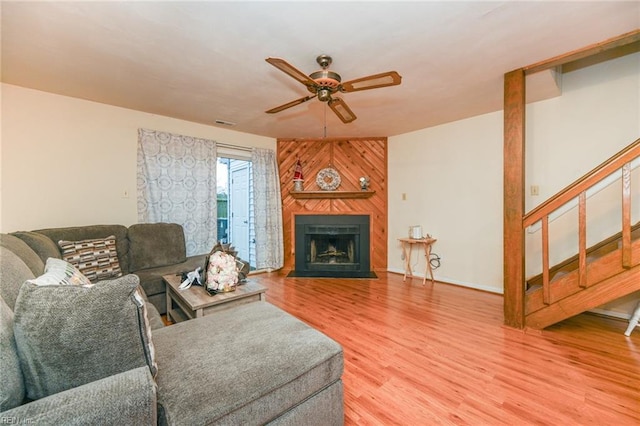 living room featuring ceiling fan, a large fireplace, and wood-type flooring