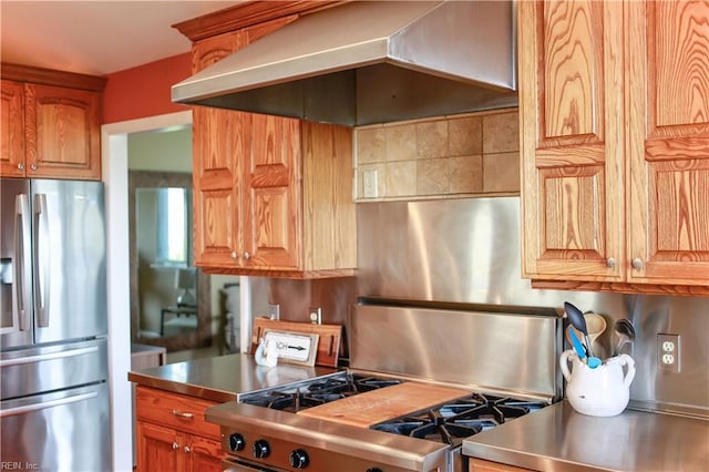 kitchen with wall chimney range hood, gas range oven, and stainless steel fridge with ice dispenser