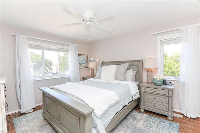 bedroom with multiple windows, ceiling fan, and light hardwood / wood-style floors