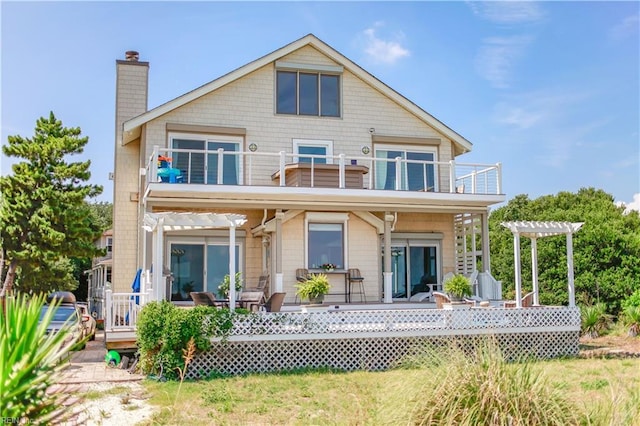 back of property featuring a balcony and a pergola