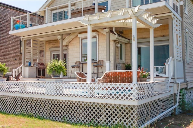 back of property featuring a wooden deck and a pergola