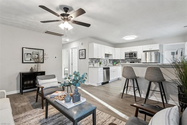 living room with ceiling fan and light hardwood / wood-style flooring