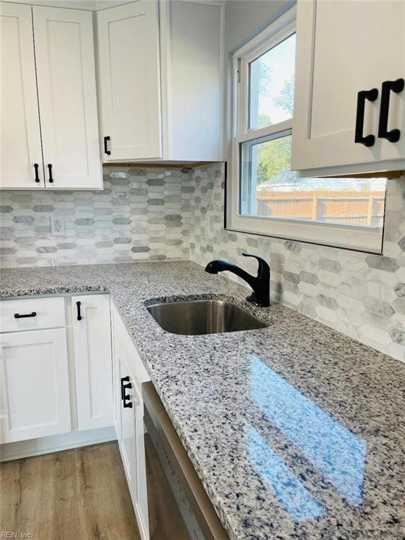 kitchen featuring white cabinetry, sink, light stone counters, and decorative backsplash