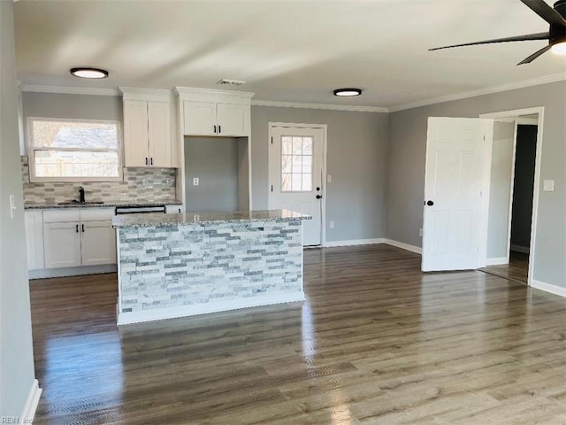 kitchen featuring ornamental molding, a center island, sink, and white cabinets