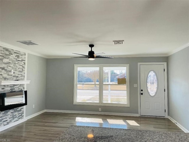 foyer entrance with crown molding, wood-type flooring, ceiling fan, and a fireplace