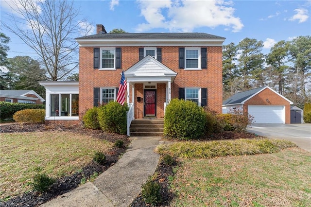 colonial home with a garage, an outdoor structure, and a front yard