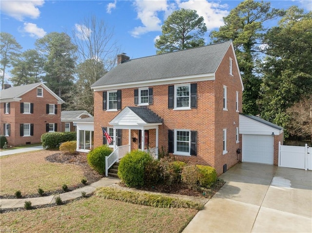 colonial home featuring a garage, an outdoor structure, and a front lawn