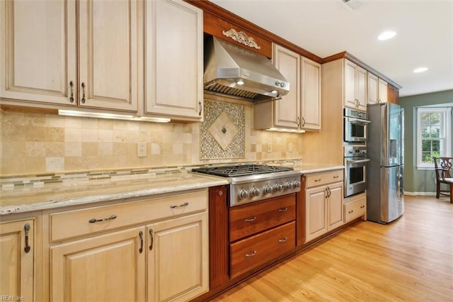 kitchen with tasteful backsplash, appliances with stainless steel finishes, light wood-type flooring, and exhaust hood