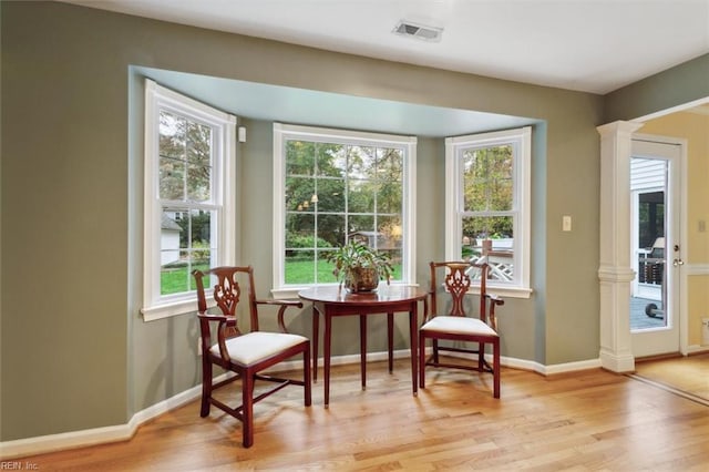 living area featuring light wood-type flooring and ornate columns