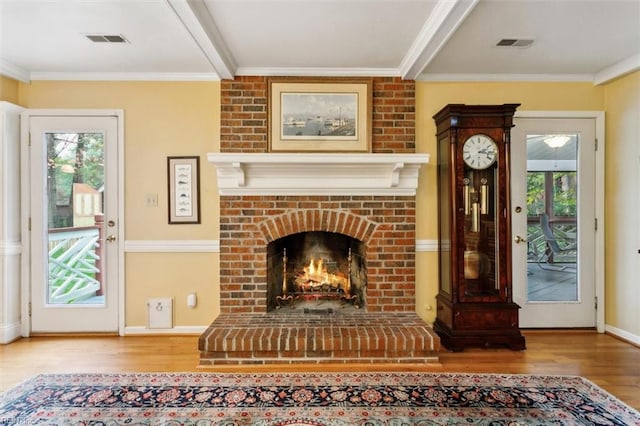 unfurnished living room with hardwood / wood-style flooring, ornamental molding, a healthy amount of sunlight, and a fireplace