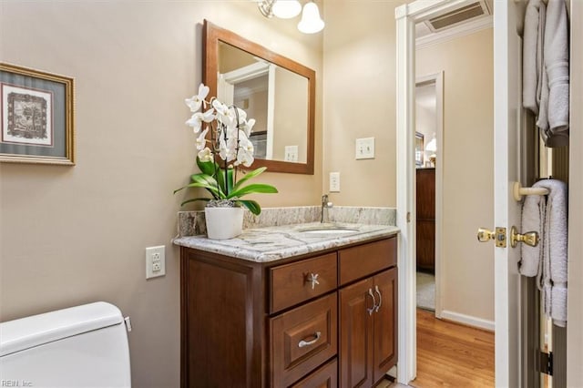 bathroom with vanity, hardwood / wood-style floors, crown molding, and toilet