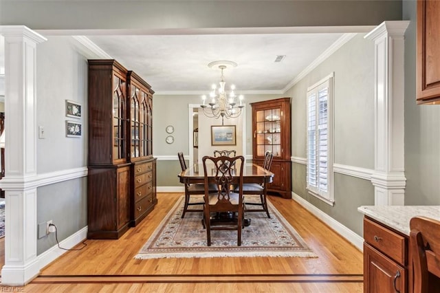 dining space with a notable chandelier, crown molding, decorative columns, and light wood-type flooring