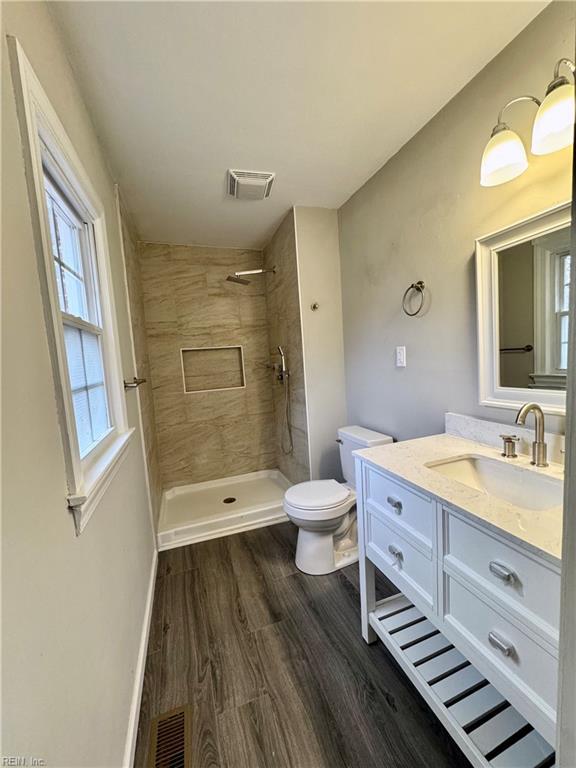 bathroom featuring tiled shower, wood-type flooring, toilet, and vanity