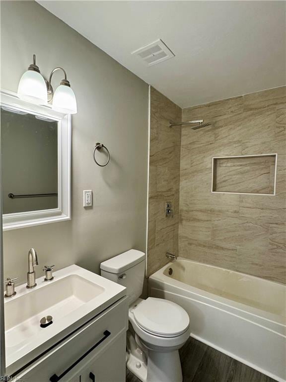 full bathroom featuring hardwood / wood-style flooring, vanity, toilet, and tiled shower / bath combo