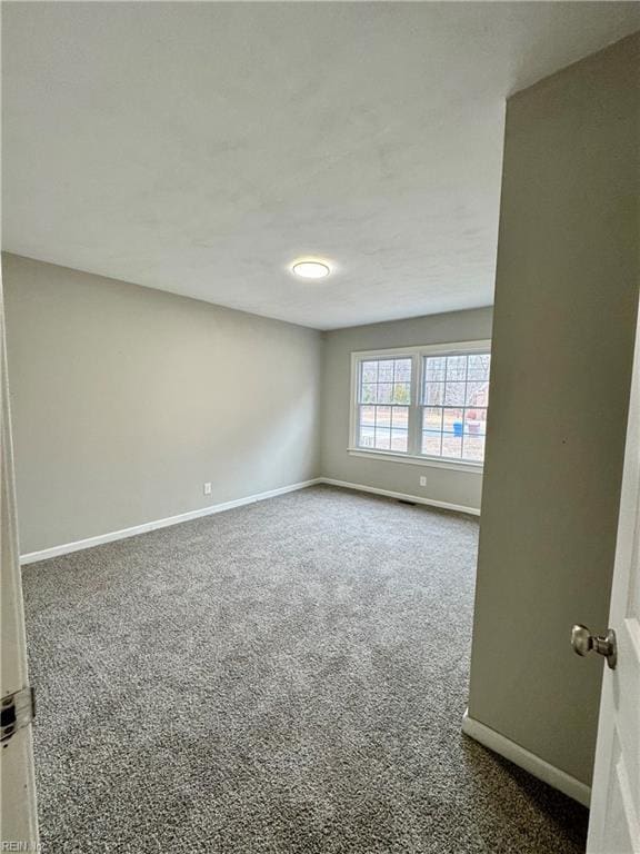 unfurnished room featuring dark colored carpet