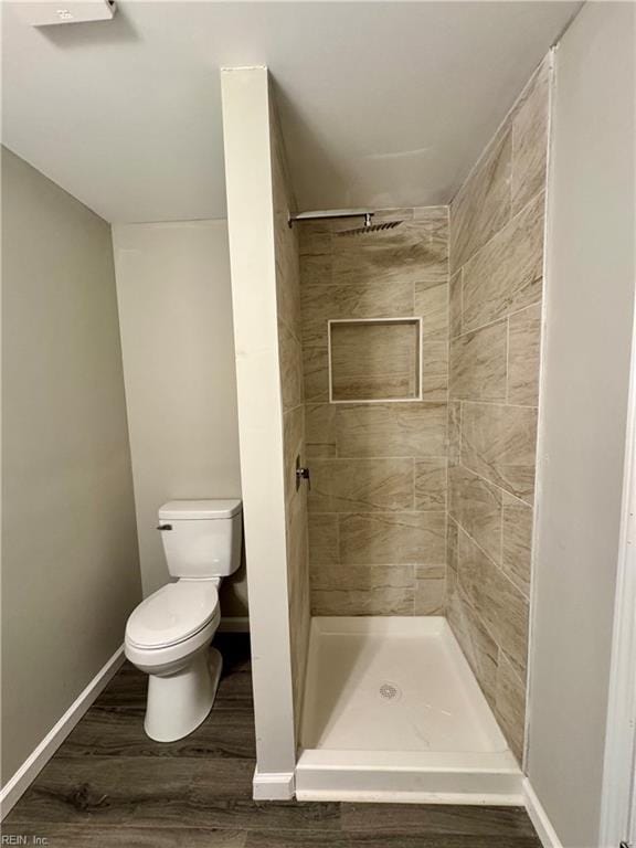 bathroom with hardwood / wood-style floors, toilet, and tiled shower