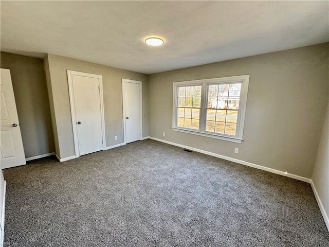 unfurnished bedroom featuring carpet flooring and two closets