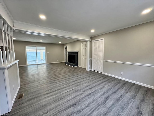 unfurnished living room with dark wood-type flooring, a fireplace, and ornamental molding