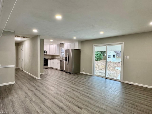 kitchen featuring appliances with stainless steel finishes, plenty of natural light, white cabinets, and light hardwood / wood-style flooring