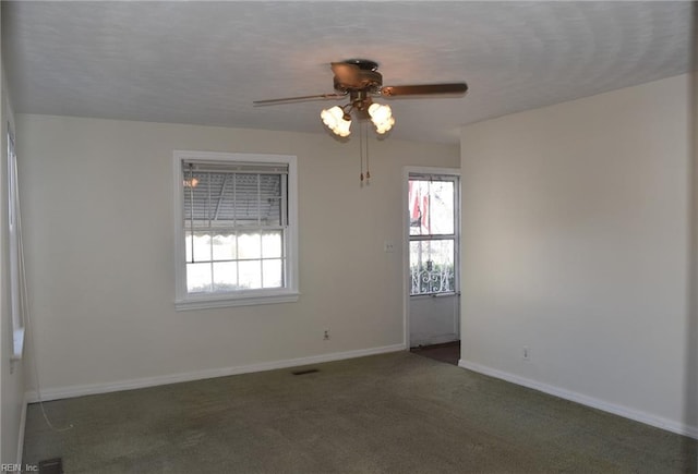 spare room featuring ceiling fan and dark carpet