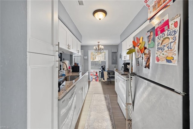 kitchen featuring sink, a notable chandelier, white appliances, light hardwood / wood-style floors, and white cabinets