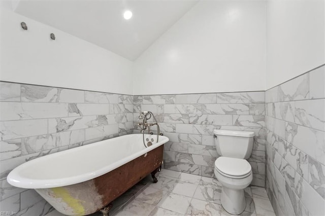 bathroom featuring toilet, vaulted ceiling, and a tub to relax in