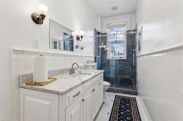 bathroom with tile walls, an enclosed shower, vanity, tile patterned floors, and toilet