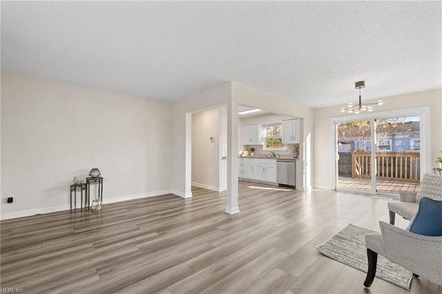 living room featuring sink, a notable chandelier, and light wood-type flooring