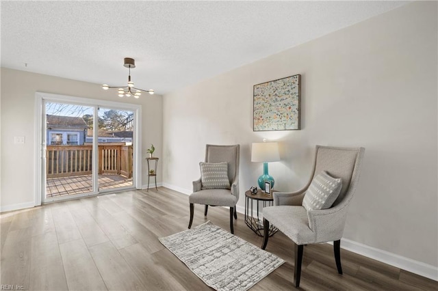 living area featuring hardwood / wood-style floors, a textured ceiling, and a chandelier