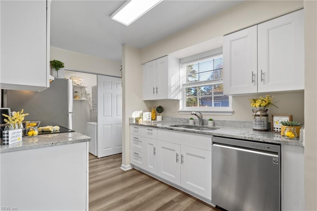 kitchen featuring stainless steel appliances, white cabinetry, sink, and light stone counters