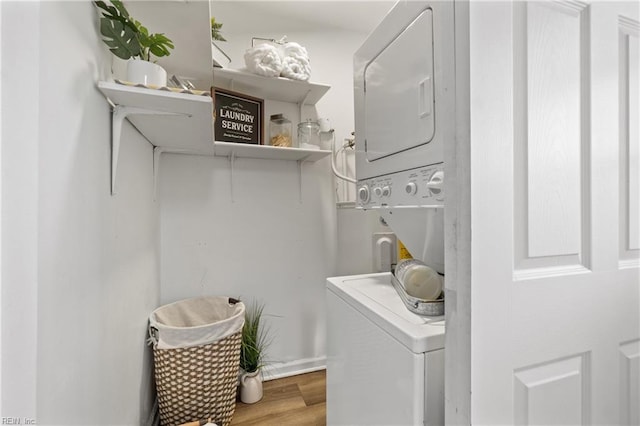 laundry room featuring stacked washer and dryer and wood-type flooring