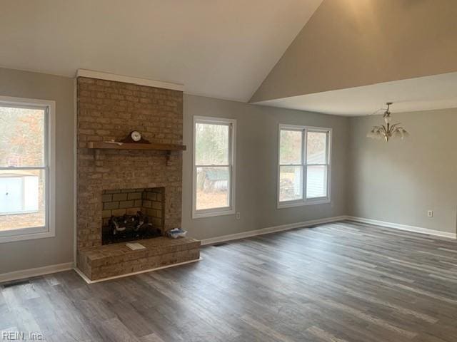 unfurnished living room featuring a brick fireplace, a notable chandelier, high vaulted ceiling, and dark hardwood / wood-style floors