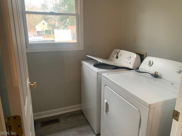 clothes washing area with hardwood / wood-style flooring and washer and clothes dryer