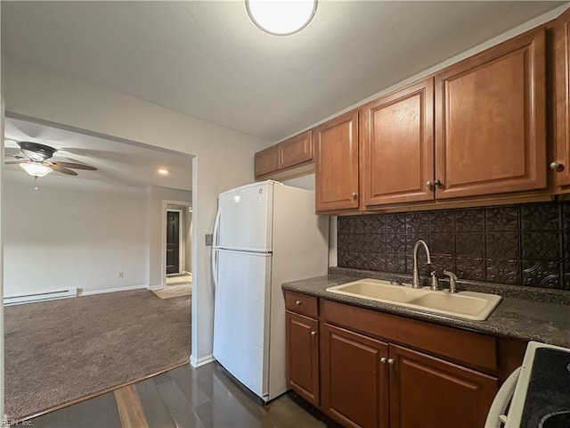 kitchen featuring sink, decorative backsplash, white fridge, a baseboard heating unit, and stove