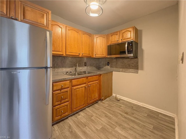 kitchen with decorative backsplash, appliances with stainless steel finishes, sink, and light hardwood / wood-style flooring