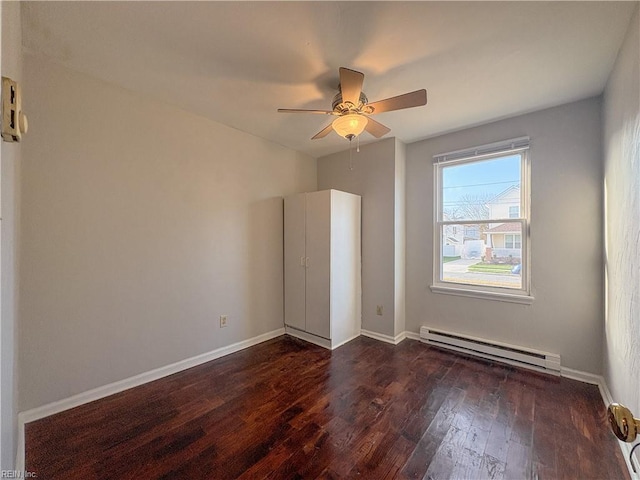 interior space with dark wood-type flooring, ceiling fan, and a baseboard heating unit