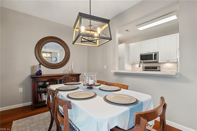 dining space with dark hardwood / wood-style floors and a chandelier